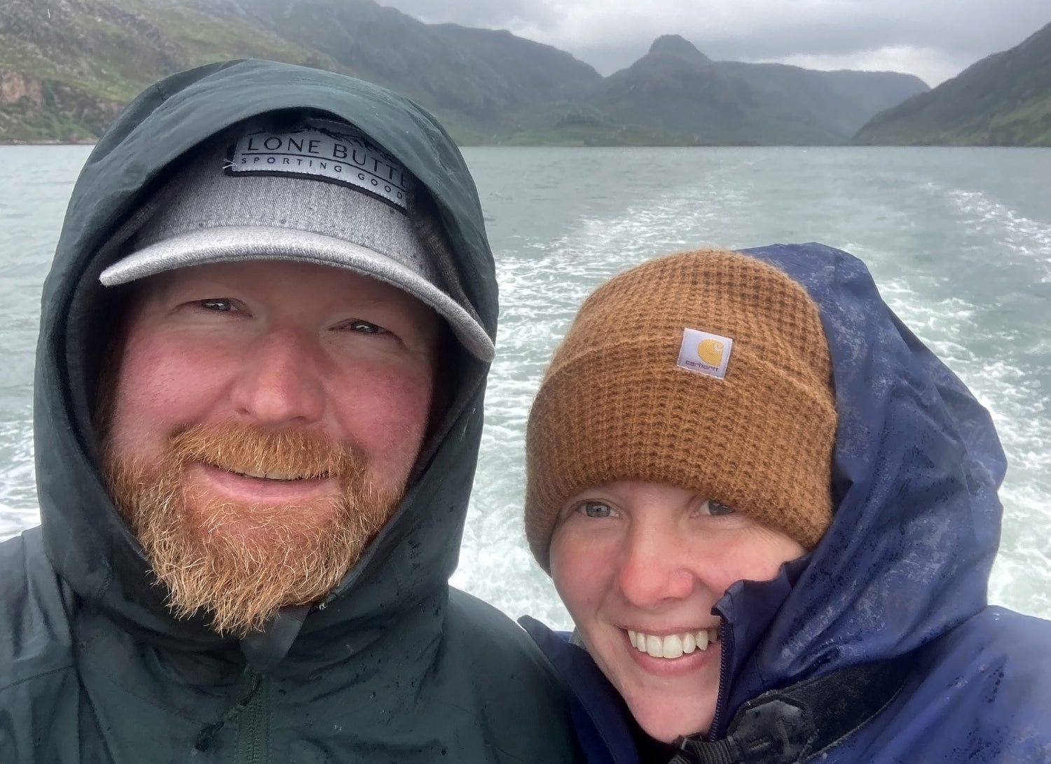 Selfie of Chris and Adele your Antler House Hosts with a view of a lake and mountains as the backdrop.